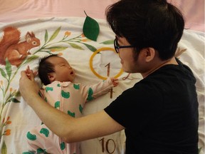 Edward Yuan and his newborn daughter at their Burnaby home earlier this month. Yuan and his wife, Eve Xiao, were stuck in Wuhan a year ago at the beginning of the global COVID outbreak.