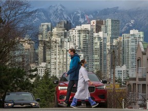 People wearing masks walk along West Broadway in Vancouver on February 25, 2021.