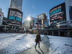 A pedestrian walks through Dundas Square in Toronto on Feb. 3. Canada has contracts to buy more vaccine doses per person than any other country, and its vaccination rates are expected to climb.