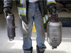 An auto wrecker employee displays two of the many types of catalytic converters thieves have been targeting.