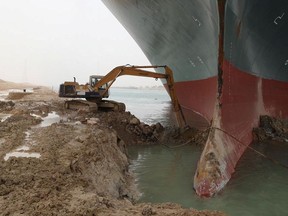 An excavator attempts to free stranded container ship Ever Given, one of the world's largest container ships, after it ran aground, in Suez Canal