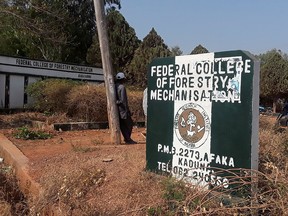 A man rests on a pole beside the signage of the Federal College of Forestry Mechanization where gunmen abducted students, in Kaduna, Nigeria March 12, 2021.