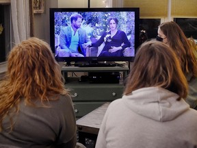 This photo illustration shows people watching a televised conversation between Prince Harry with his wife Meghan Markle and host Oprah Winfrey, in Arlington, Virginia March 7, 2021.