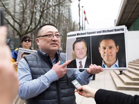 Louis Huang of Vancouver Freedom and Democracy for China holds a photo of Canadians Michael Spavor and Michael Kovrig, who are being detained by China, outside B.C. Supreme Court, in Vancouver, March 6, 2019.