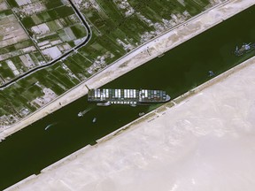 This handout satellite image courtesy of Cnes 2020 released on March 25, 2021 by Airbus DS shows the Taiwan-owned MV ‘Ever Given’ (Evergreen) container ship, a 400-metre (1,300-foot) long and 59-metre wide vessel, lodged sideways and impeding all traffic across the waterway of Egypt’s Suez Canal.