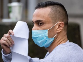 Mohammad Movassaghi tries to hide his face with a copy of his release order as he leaves Vancouver Police Department jail in Vancouver on Sunday, January 31, 2021. Police arrested a man who allegedly operated a makeshift nightclub at his Vancouver penthouse and issued fines against him and his suspected guests totalling more than $17,000.