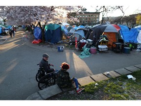 People sit near a homeless encampment at Oppenheimer Park in April 2020.