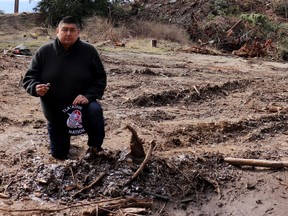 Hegus (Chief) John Hackett at the Tla'amin Nation's archeological village and burial site north of Powell River. Hackett is holding is holding some of the shell midden in his right hand from the exposed bed at his feet.