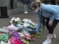 A woman lays flowers at the scene of a mass stabbing which left one person dead at the Lynn Valley Library.