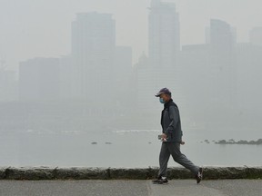 A man walks along the Stanley Park Seawall as smoke from wildfires in neighbouring Washington state shrouds Vancouver's skyline.