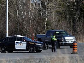 A police officer stops a motorist at a police checkpoint at the Manitoba-Ontario provincial boundary.