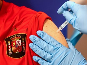 A man, wearing a t-shirt with the logo of the Spanish National soccer team, receives his first dose of the AstraZeneca COVID-19 vaccine, at Enfermera Isabel Zendal hospital in Madrid, Spain, Tuesday, April 6, 2021.
