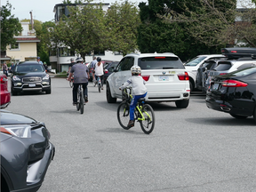 Cyclists on the Seaside Greenway mixing with cars in the Kits Beach parking lot.