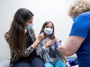 Marisol Gerardo, 9, is held by her mother as she gets the second dose of the Pfizer vaccine during a clinical trial for children at Duke Health in Durham, N.C., on April 12. It's unclear what role the vaccination of kids will play in achieving herd immunity in B.C.
