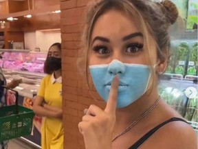 In this screenshot, Se is seen holding a finger to her lips as she attempts to enter a Bali supermarket with a painted mask on her face.