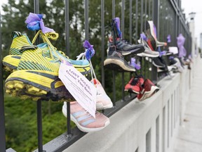 Shoes with a personal message hang on the fence on the Burrard Street Bridge as part of the awareness-raising art display, Lost Soles: Gone Too Soon, with each pair of shoes representing a life lost to a drug overdose, in Vancouver on Aug. 30, 2020. The display was organized by Moms Stop the Harm.