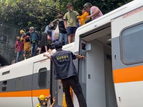 Rescue team help stranded passengers down from the roof of a train which derailed in a tunnel north of Hualien, Taiwan April 2, 2021, in this still image taken from video.