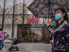 People walk by an H&M clothing store at a shopping area on March 30, 2021 in Beijing, China.