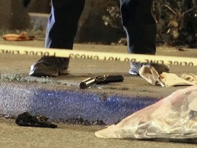 A police officer stands guard over a .45-calibre pistol with a silencer lying on a sidewalk after a targeted shooting outside Cardero's restaurant in Coal Harbour on April 17, 2021, in Vancouver.