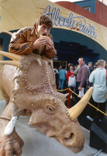 Expo 86 Pavilions. Getting in the mood to face the Lions is Calgary's Rob Smith, who munches on buffalo burger astride stegosauus outside Alberta pavilion. Ran June 17, 1986 pg. F 5 Vancouver Sun. Peter Battistoni Vancouver Sun. TC # 86-3089 Sunday feature Expo 86 30th anniversary [PNG Merlin Archive]