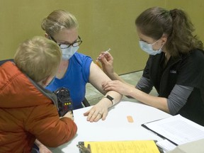 Shannon Akester, a math teacher at Panorama Ridge Secondary School, gets her COVID-19 vaccine from Fraser Health registered nurse Anisa Wohlleben while son David Akister looks on in Surrey on March 24, 2021.
