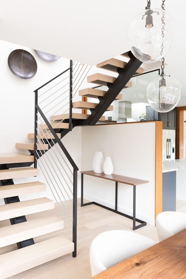 An open staircase and glass panel keep sightlines clear through the main floor.