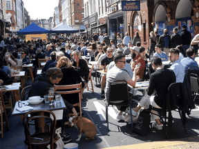 People packed on a London restaurant patio as COVID lockdown restrictions eased in Britain, April 24, 2021. In the space of three months, the U.K.’s daily average death toll dropped from 1,244 to 26; it is now at 13.