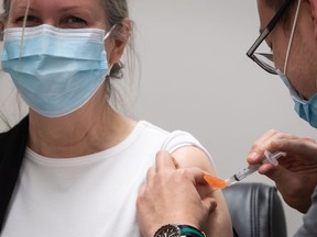 Pharmacist Mario Linaksita, right, administers the Oxford-AstraZeneca COVID-19 vaccine to Sharon Berringer, 56, at University Pharmacy, in Vancouver, on Thursday, April 1, 2021.