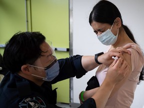 Rajdeep Birring receives her first dose of the Pfizer COVID-19 vaccine from from Surrey firefighter Justin Sayson at a walk-up vaccination clinic at Bear Creek Park.