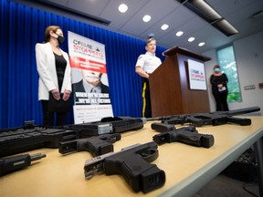 Seized firearms are displayed as RCMP Assistant Commissioner Dwayne McDonald speaks during an RCMP and Crime Stoppers news conference at RCMP headquarters in Surrey on May 17, 2021. The B.C. government is providing $200,000 to Metro Vancouver Crime Stoppers to try and help police make arrests and solve gang-related crimes.