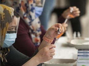 Nurses prepare syringes with the Pfizer COVID-19 vaccine at the Dukh Nivaran Sahib Gurwara in Surrey on Friday.