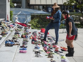 Two hundred and fifteen pairs of kids shoes line the steps of the Vancouver Art Gallery on Friday in response to the revelation that 215 children's remains were discovered this week at the site of the former Kamloops residential school. The shoes were placed on the steps by First Nations advocates from the Downtown Eastside.