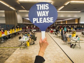 Volunteer Jayne Ralphs directs people to a station as thousands get their vaccine shot at Vancouver Trade and Convention Centre (East)  in Vancouver, BC, May 10, 2021.