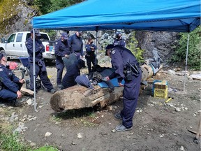 Individual on a log with his arm attached to a locking device inside the log.