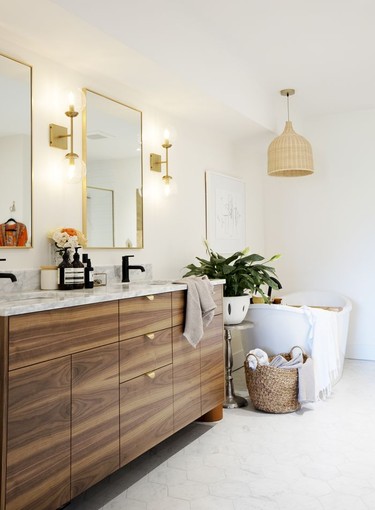 The ensuite off the primary bedoom features warm gold and natural basket weave accents, a deep soaker tub and a vast closet made from IKEA Pax wardrobe modules.