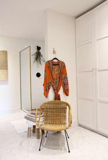 The ensuite off the primary bedoom features warm gold and natural basket weave accents, a deep soaker tub and a vast closet made from IKEA Pax wardrobe modules.