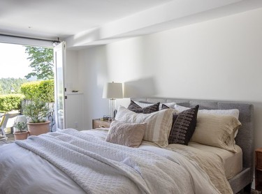 Cool but cosy linens and natural-texture cushions are heaped in the primary bedroom, which looks out over Deep Cove.