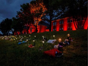 Shoes, flowers, and stuffed animals sit outside the former Kamloops Indian Residential School where flowers and cards have been left as part of a growing makeshift memorial to honour the 215 children whose remains have been discovered buried near the facility in Kamloops on June 5, 2021.