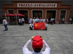 This photo taken on June 11, 2021 shows people with a flag of the Chinese Communist Party posing next to the museum of the First National Congress of the Chinese Communist Party in Shanghai.