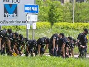 11 London police officers perform a search shoulder to shoulder along the southbound lanes of Hyde Park Road looking for evidence after a quadruple fatality at South Carriage Road and Hyde Park on Sunday evening in London, Ont.