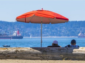 People sit in the shade at Ambleside beach, West Vancouver.