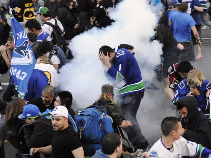  Canucks fans move along West Georgia as police discharge flash bangs into the crowd after the reading of the riot act.