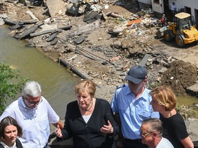 German Chancellor Angela Merkel (second from left) and Rhineland-Palatinate State Premier Malu Dreyer (right) talk as they stand on a bridge during their visit in the flood-ravaged areas on July 18, 2021 in Schuld, near Bad Neuenahr-Ahrweiler, Rhineland-Palatinate state, in western Germany.