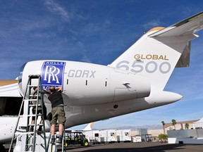 Workers apply a Rolls Royce decal to the engine of a Bombardier Global 6500 business jet at the Bombardier booth at the National Business Aviation Association (NBAA) exhibition in Las Vegas, Nevada, Oct. 21, 2019.