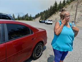 Martha Van Dyke of Lytton stands next to her car after a wildfire that raged through her town and forced residents to evacuate outside of Lytton on July 1, 2021.