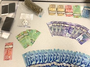 In this handout photo, Burnaby police showcase a stash of suspected drugs, cash and cell phones they seized from suspects.