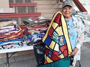 An elder examines one of 200 quilts during an event at the July 10 at the Tk’emlúps te Secwépemc Nation's powwow grounds in Kamloops for fire evacuees.