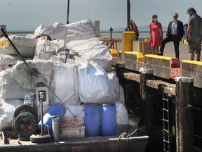 Officials look over a barge stacked with bales of plastic waste at the official opening of Ocean Legacy Foundation's new plastic processing facility at the Steveston Harbour in Richmond.