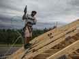 A worker nails plywood on the roof of a home under construction.