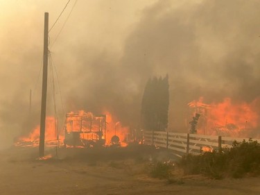 Flames rise from a burning building along a street during a wildfire in Lytton, British Columbia, Canada June 30, 2021 in this still image obtained from a social media video on July 1, 2021.